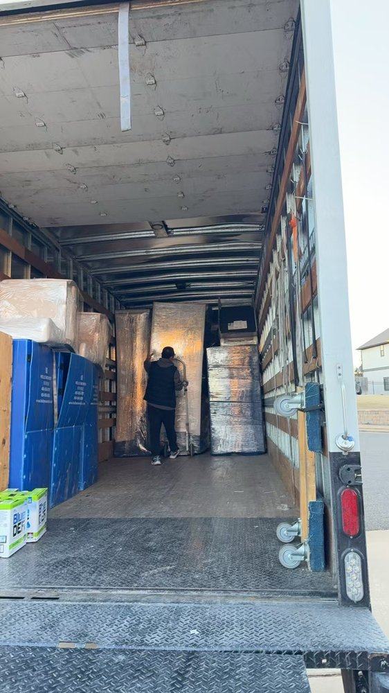 A mover arranging wrapped furniture inside a box truck
